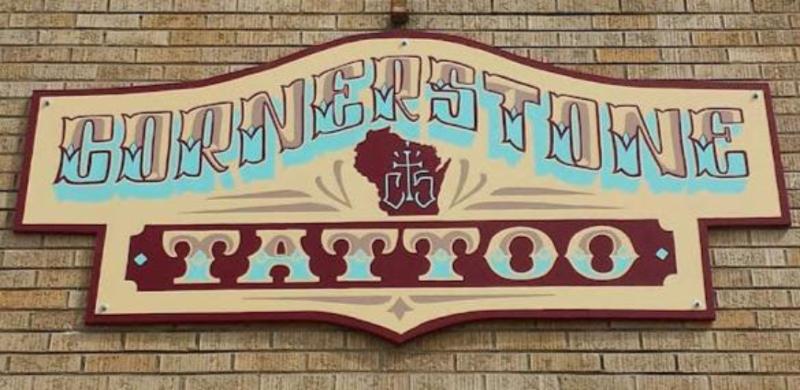 handpainted sign for cornerstone tattoo on a brick wall